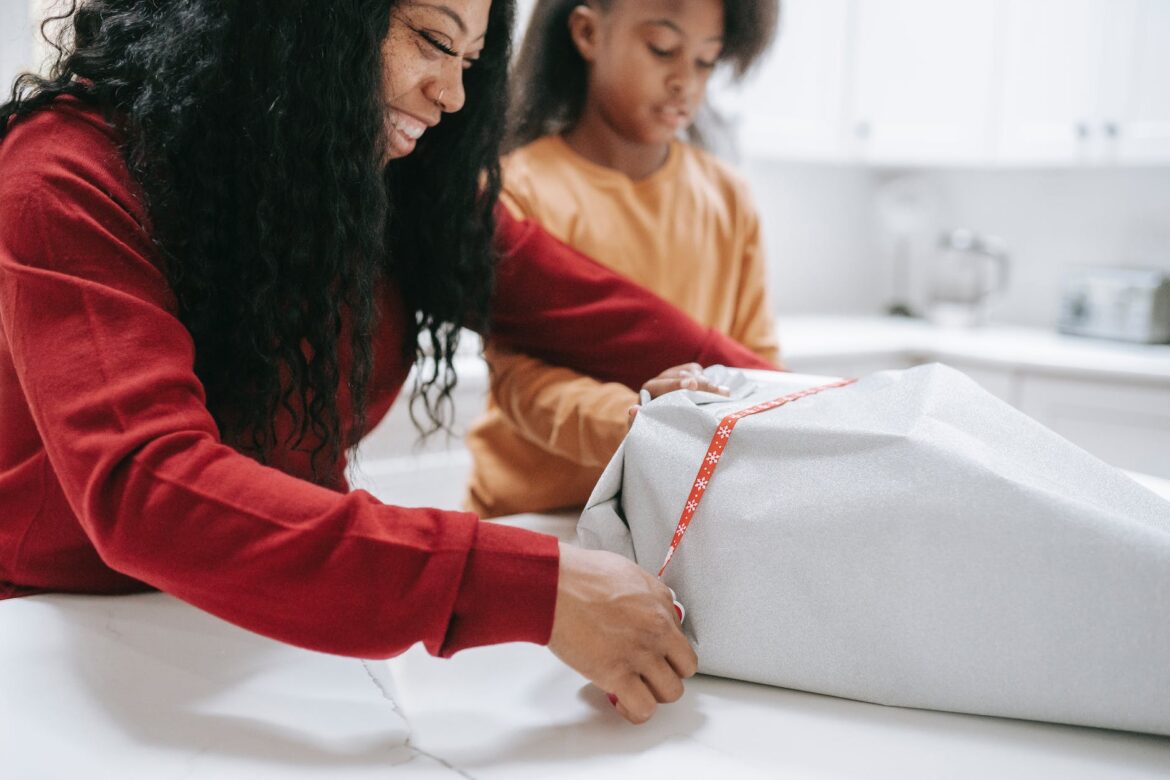 happy african american woman packing gift boxes with daughter